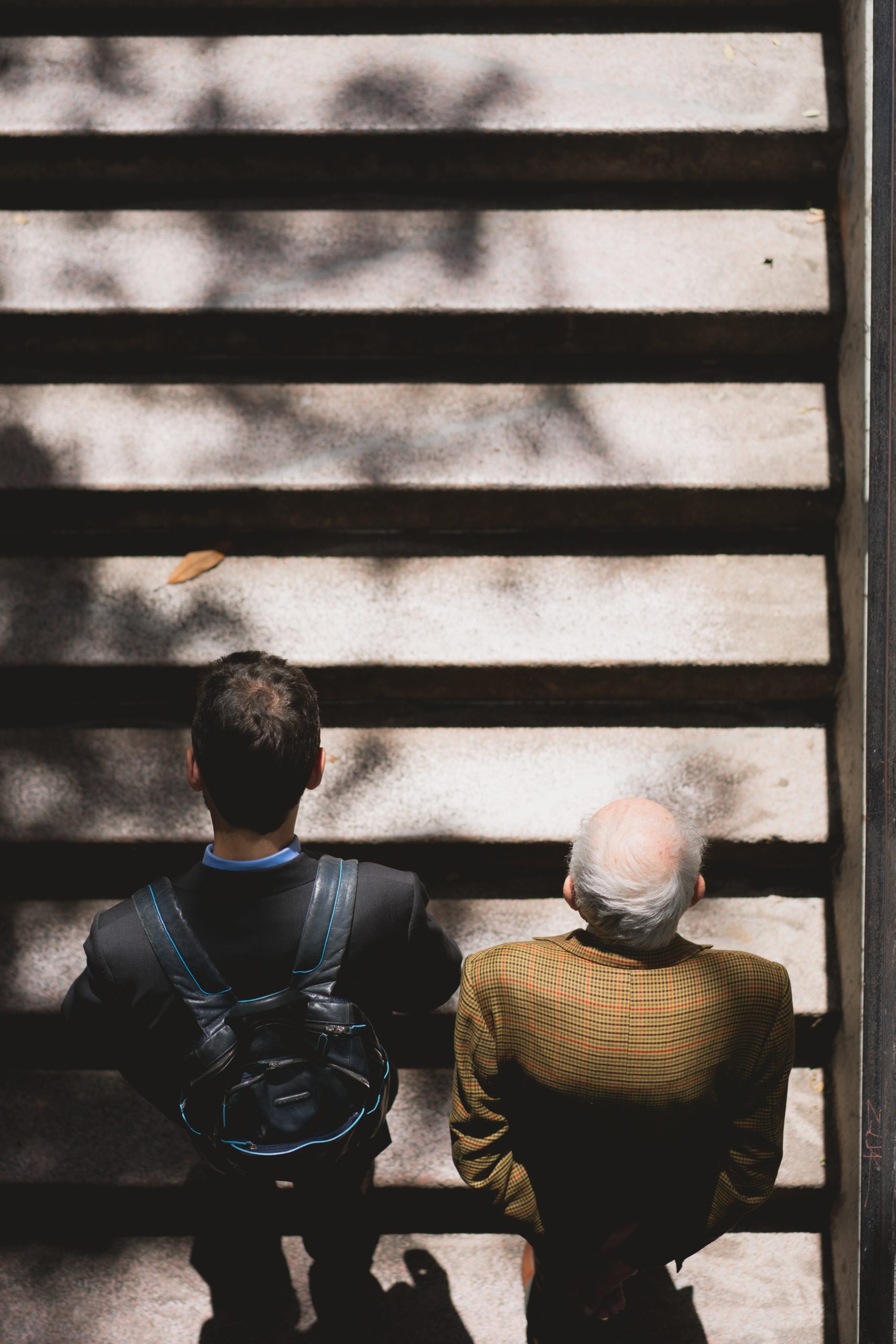 A younger man walks up the stairs with an older man