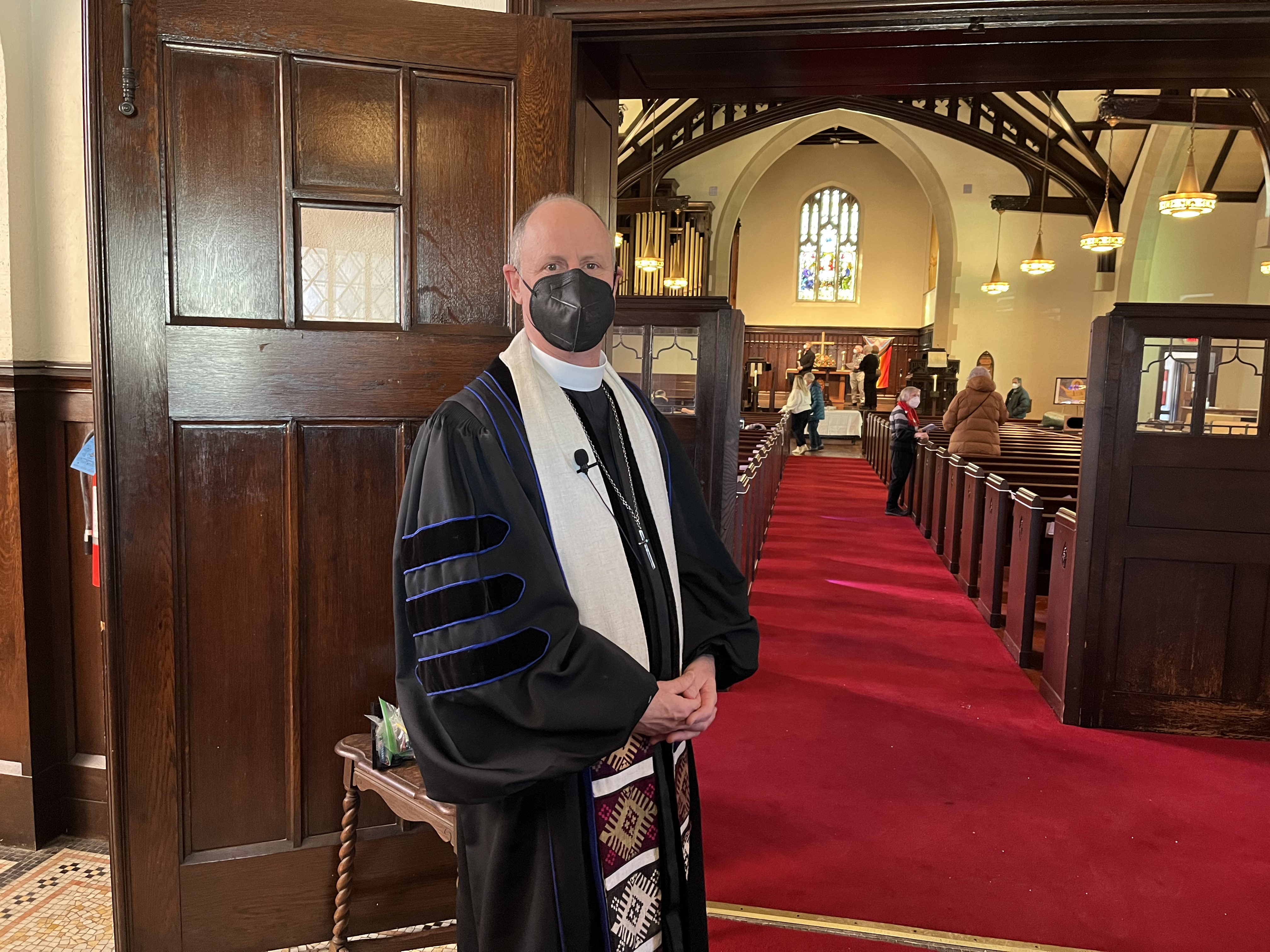 The Reverend Ken Baily standing before an open door to the sanctuary