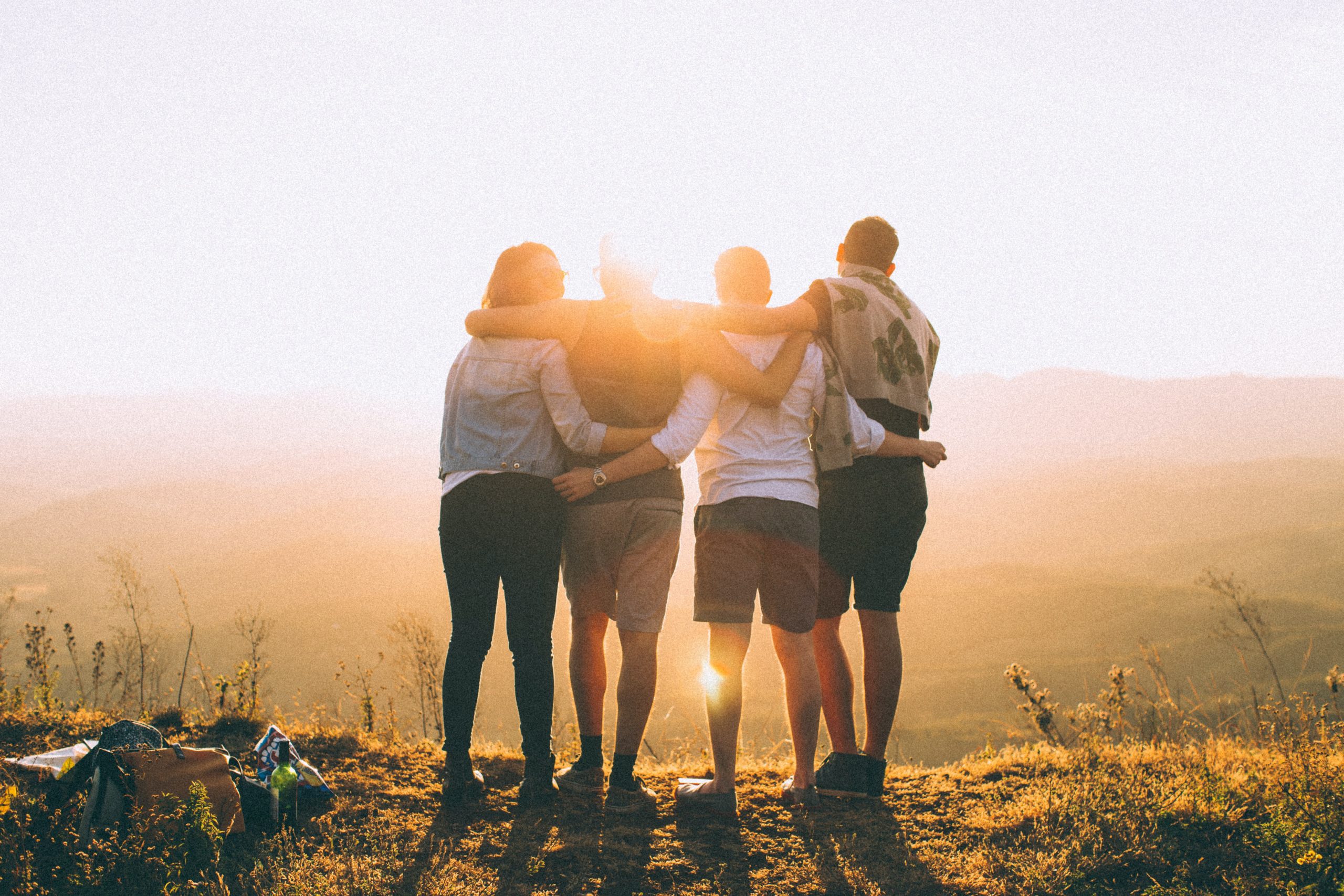 four people arms linked looking at sunset