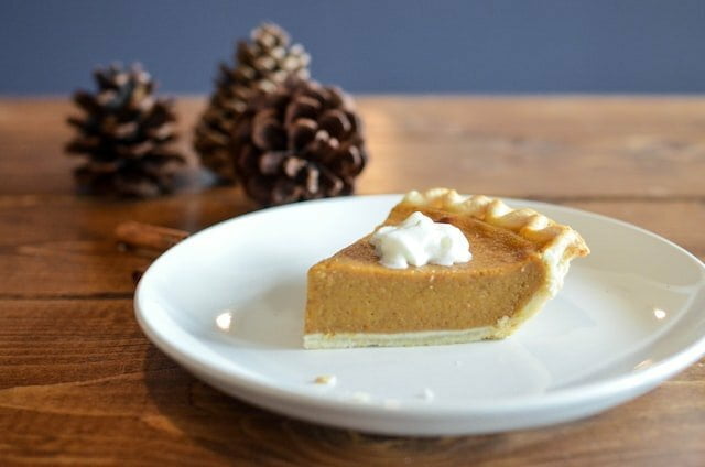 slice of pumpkin pie with two pine cones