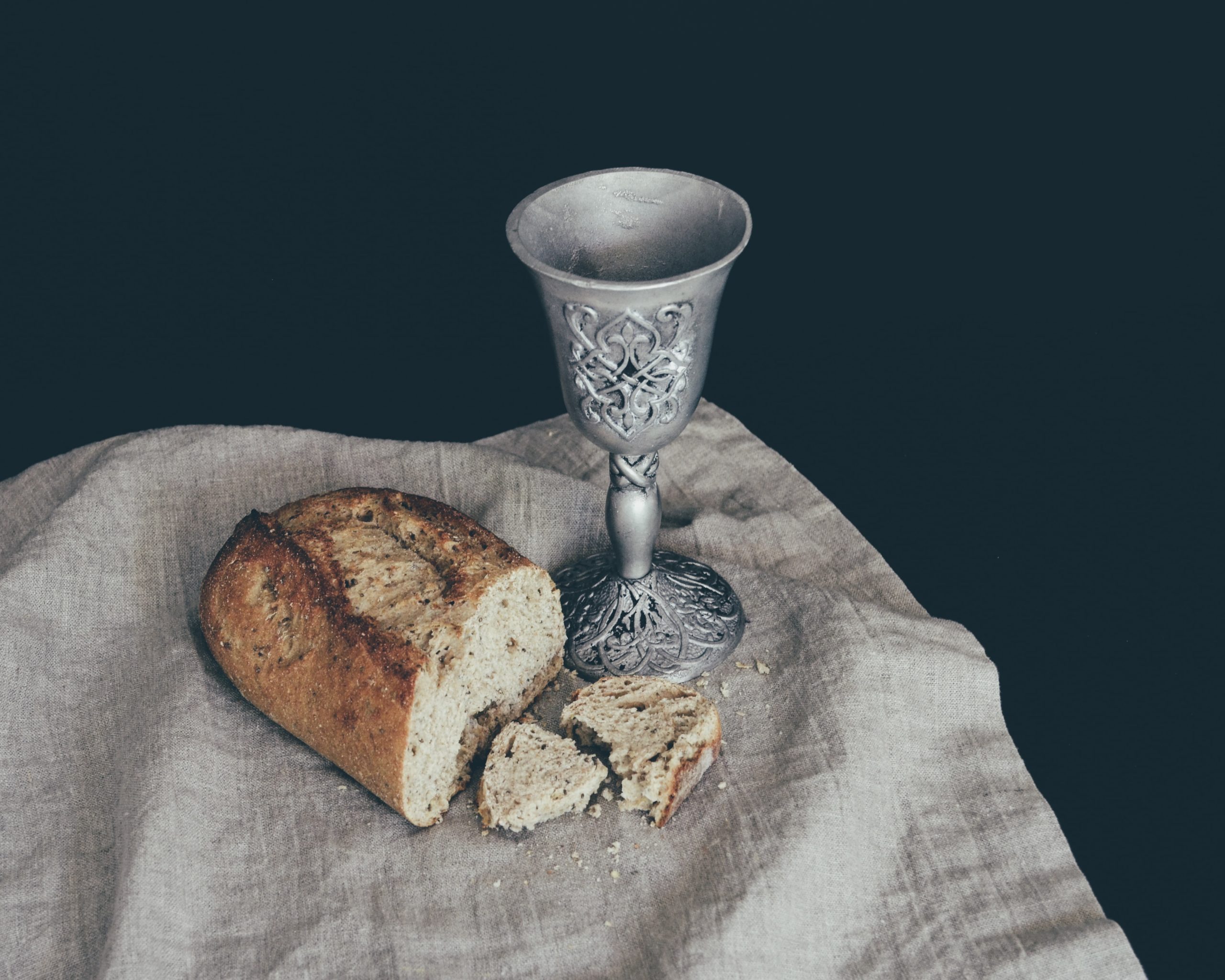 piece of bread with goblet on white cloth