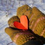 Mitten-clad hands holding red paper heart