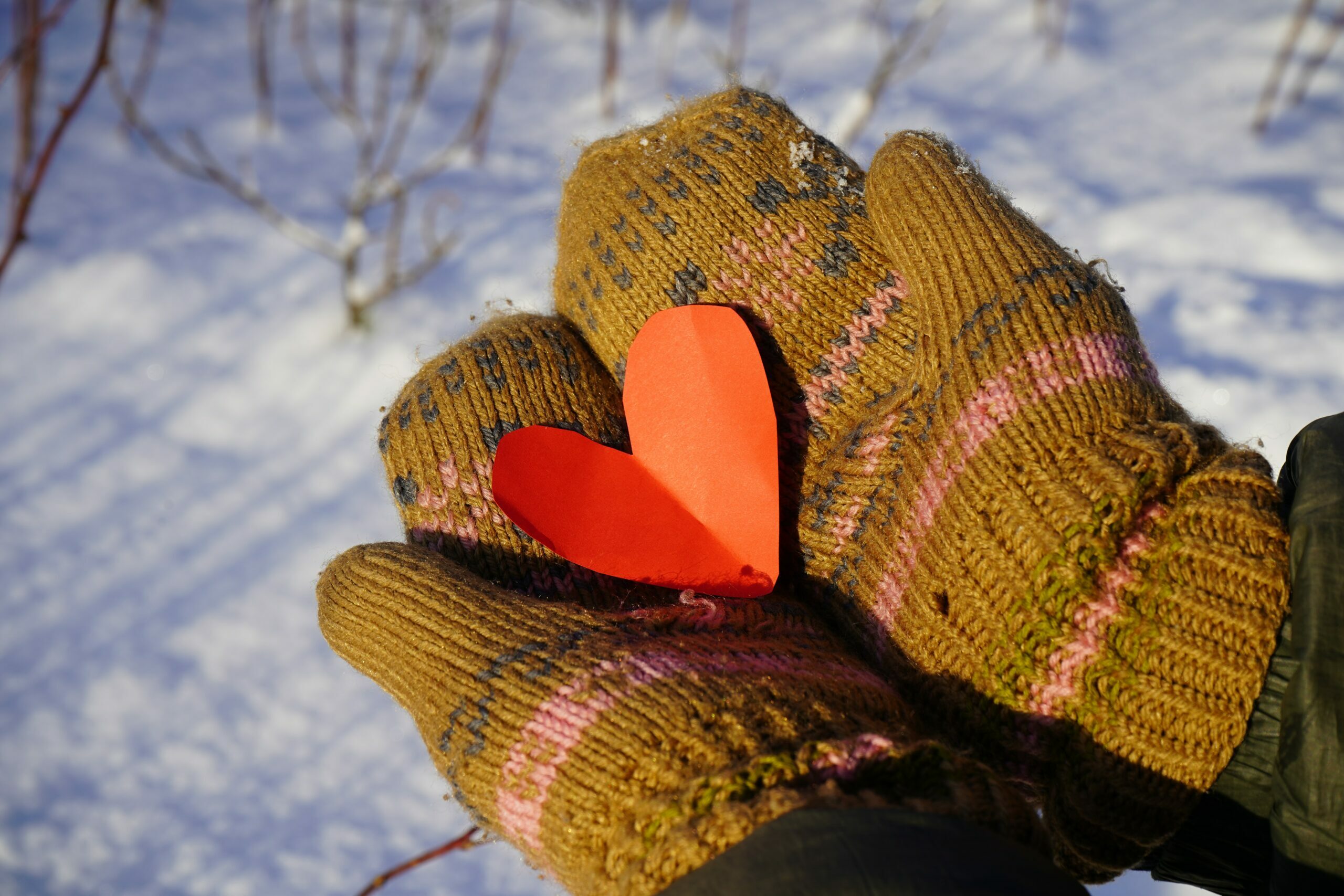 Mitten-clad hands holding red paper heart