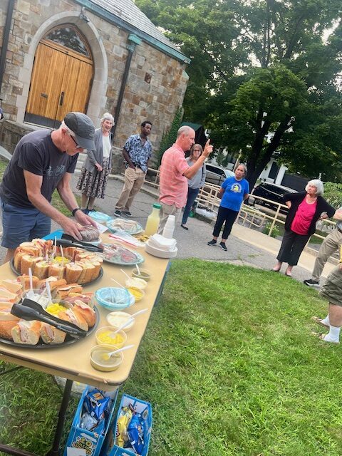 Man arranging refreshments and worshippers in circle on church lawn