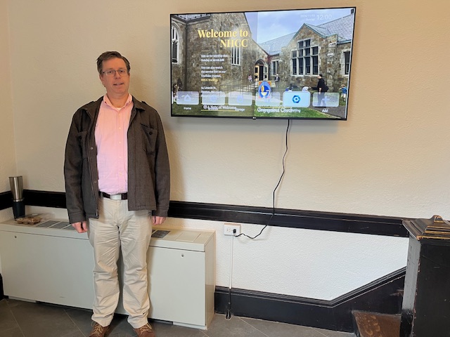 man next to screen on wall