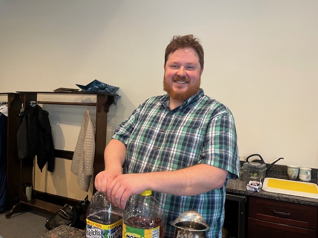 Smiling Ted Pales with bottles of juice in parlor