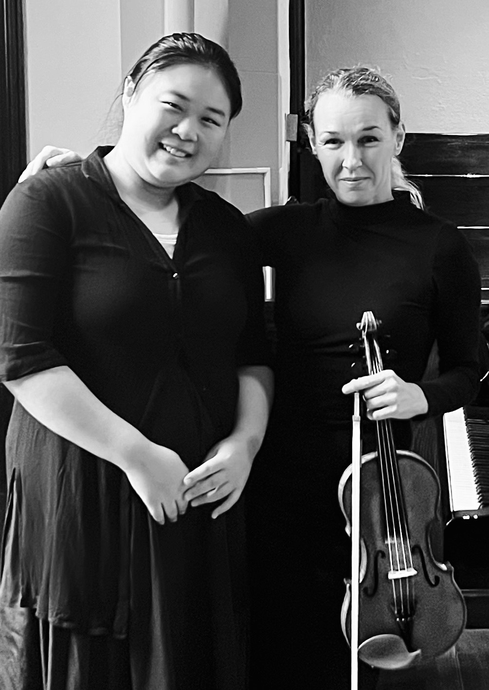 Two female musicians, one holding violin, smiling in sanctuary,