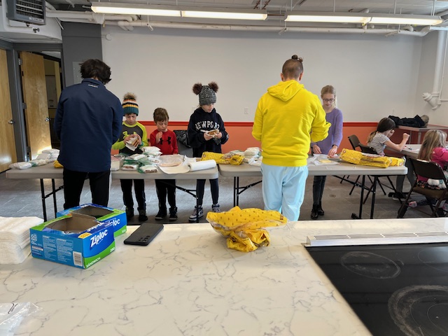 children and leaders making sandwiches at long tables