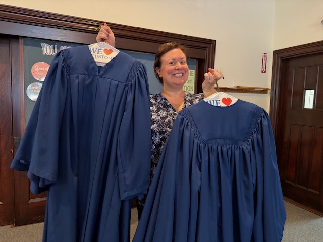 Music director Jan Zimmerman holding blue choir robes.