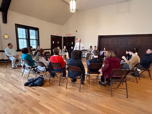 group of young people and adults listening to a minister