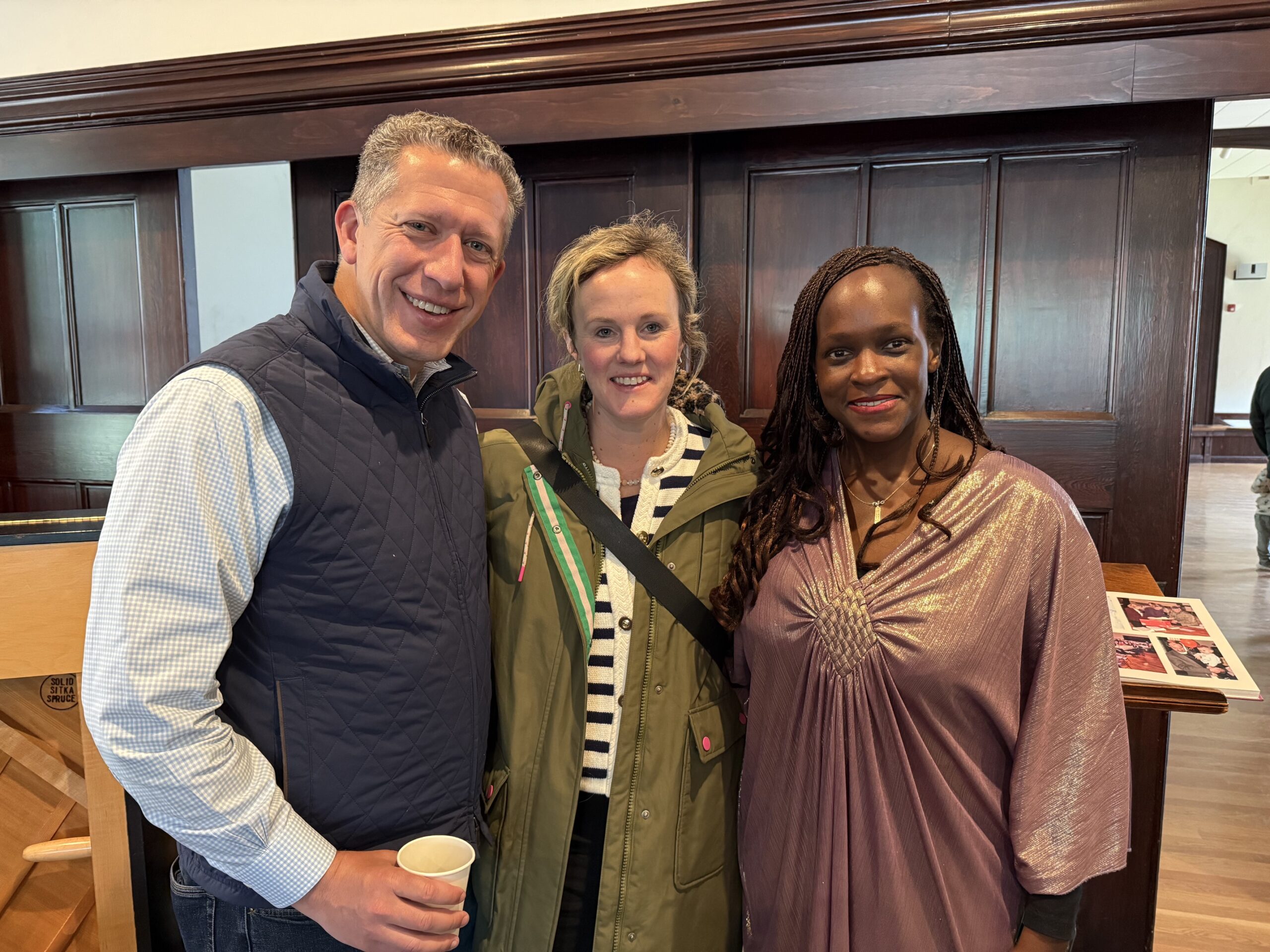 Man and two women smiling in church parlor